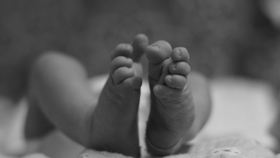 Das Bild zeigt die Füße eines Neugeborenen in schwarz-weißer Großaufnahme